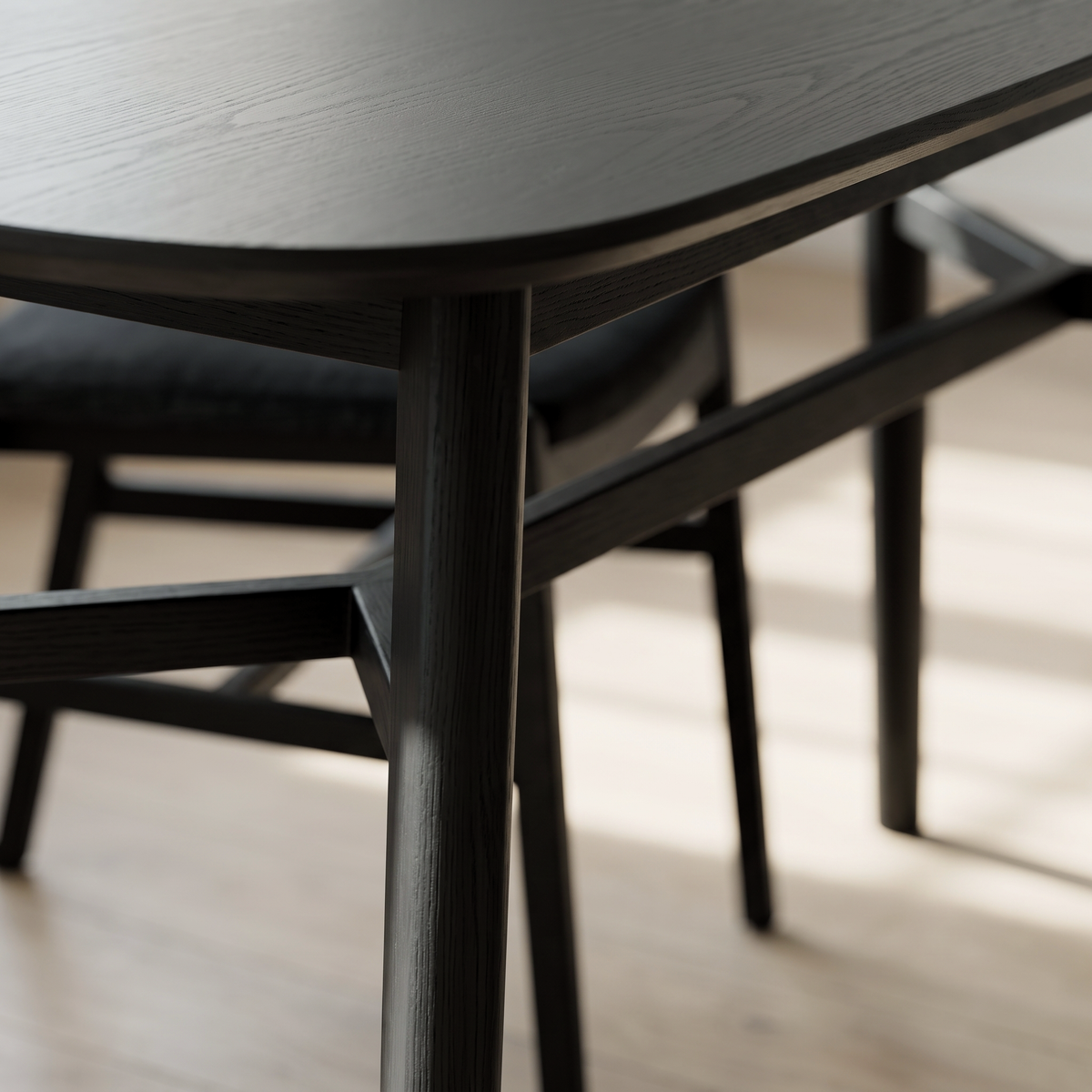 Modern minimalist dining room featuring a sleek black wooden table and matching chair on light hardwood flooring.