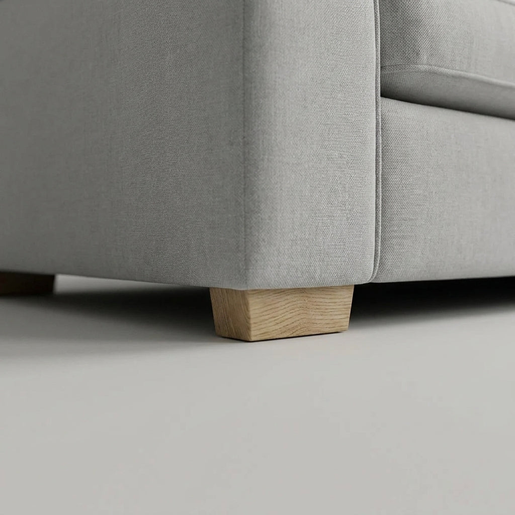 Close-up of a modern light gray fabric sofa with natural wooden legs, showcasing minimalist interior design style.