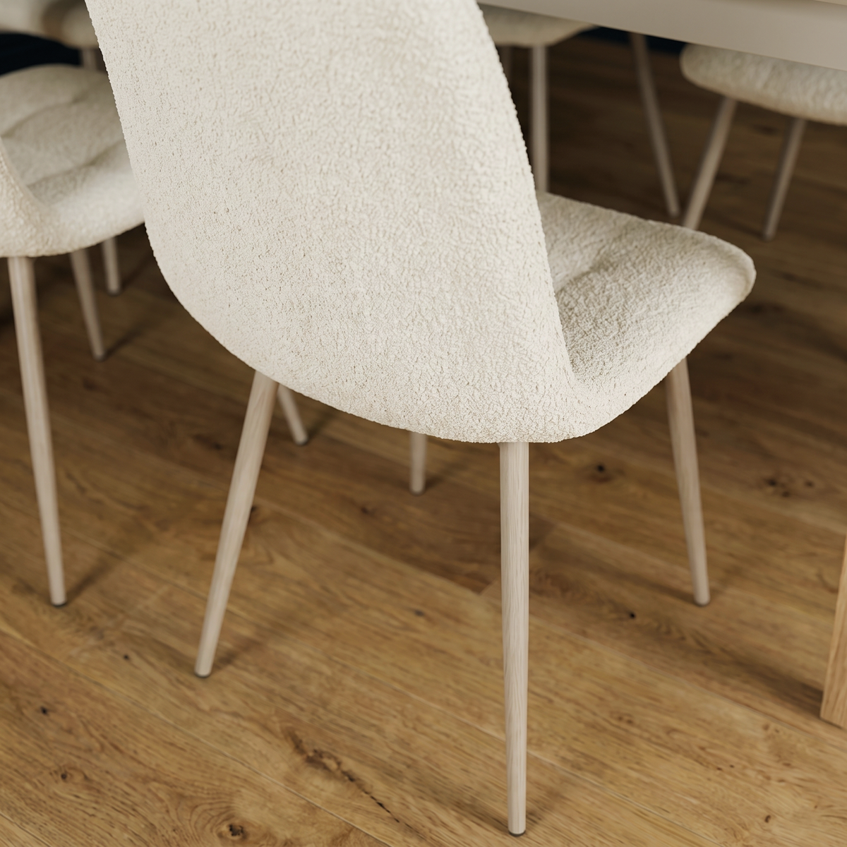 Close up of a Brianna dining chair showing the cream boucle upholstery and the slim tapered pale legs