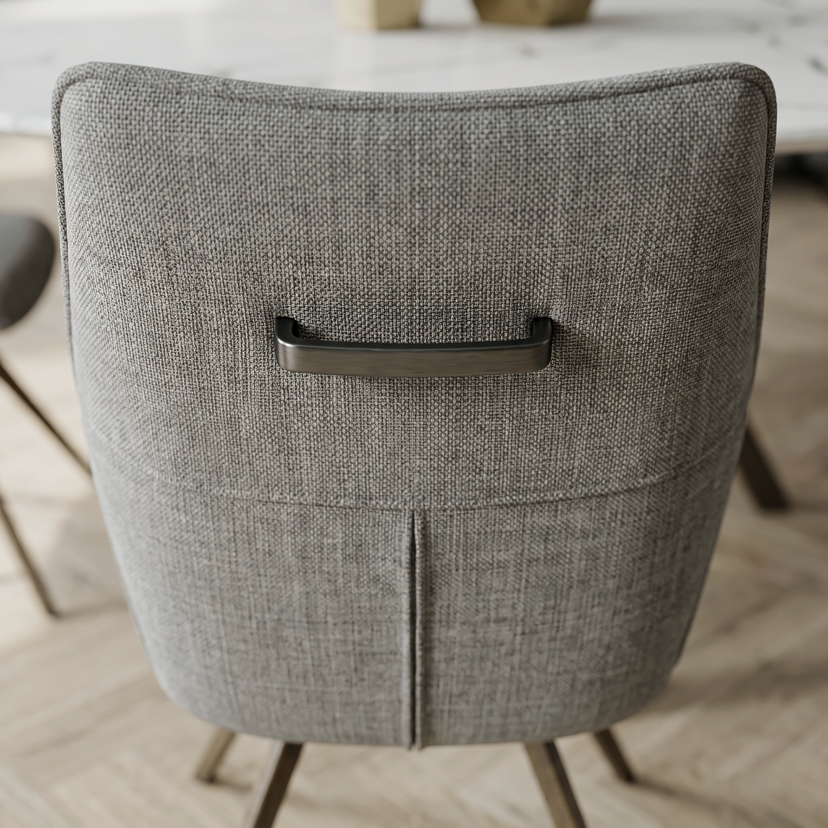 Close up of the back of a Porthos dining chair showing the dark metal strap handle set into the grey woven fabric