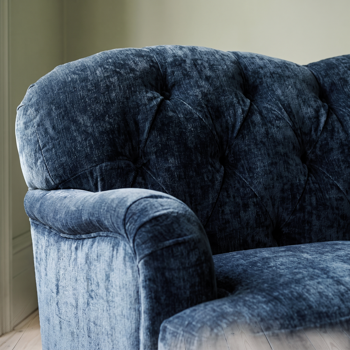 Close up of the deep button tufting and rolled scroll arm on the Ellise navy chenille sofa