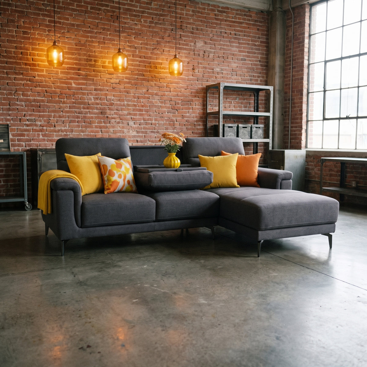 Warwick charcoal grey chaise lounger sofa with drop down tray, in a loft room with exposed brick and polished concrete