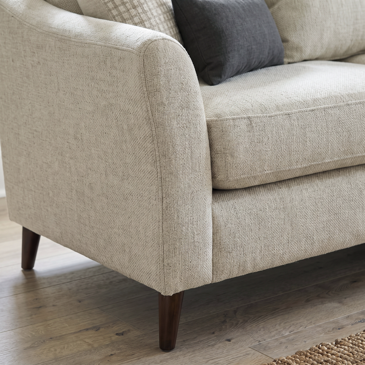 Close up of the flared arm, piped seam and dark tapered wooden leg on the Samantha sofa