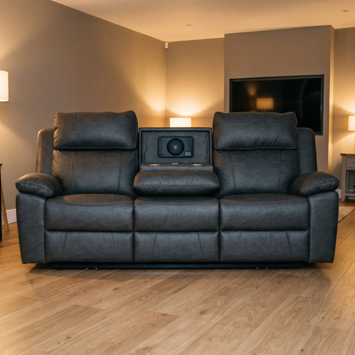 Tiberius three seater reclining sofa in charcoal grey with drop down console and speaker, in a warm living room with oak flooring