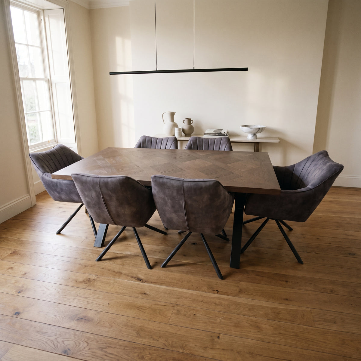 Winston 180cm dark wood dining table with six grey tub chairs in a bright room with oak floorboards and a black linear pendant
