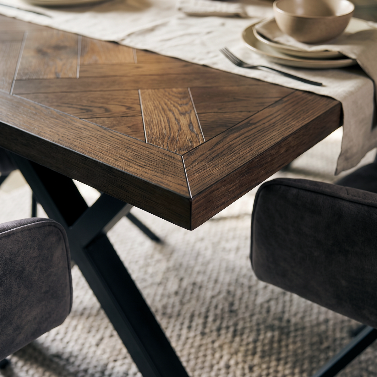 Close up of the herringbone parquet top and black splayed metal leg on the Winston dining table