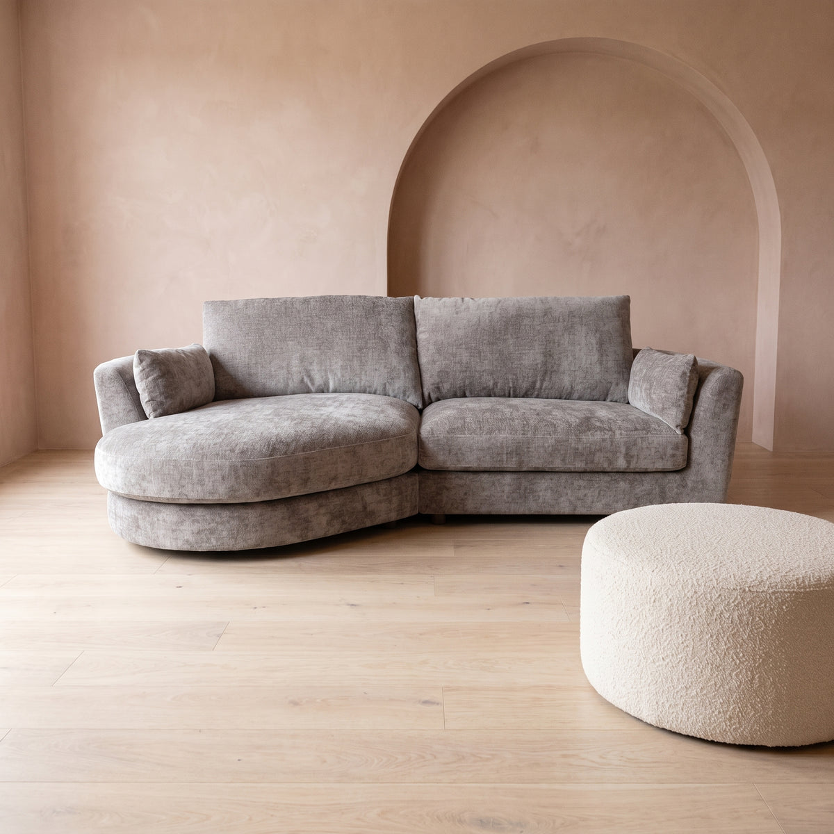 Persia curved chaise end sofa in soft grey chenille, in a room with warm plaster pink walls and a pale oak floor