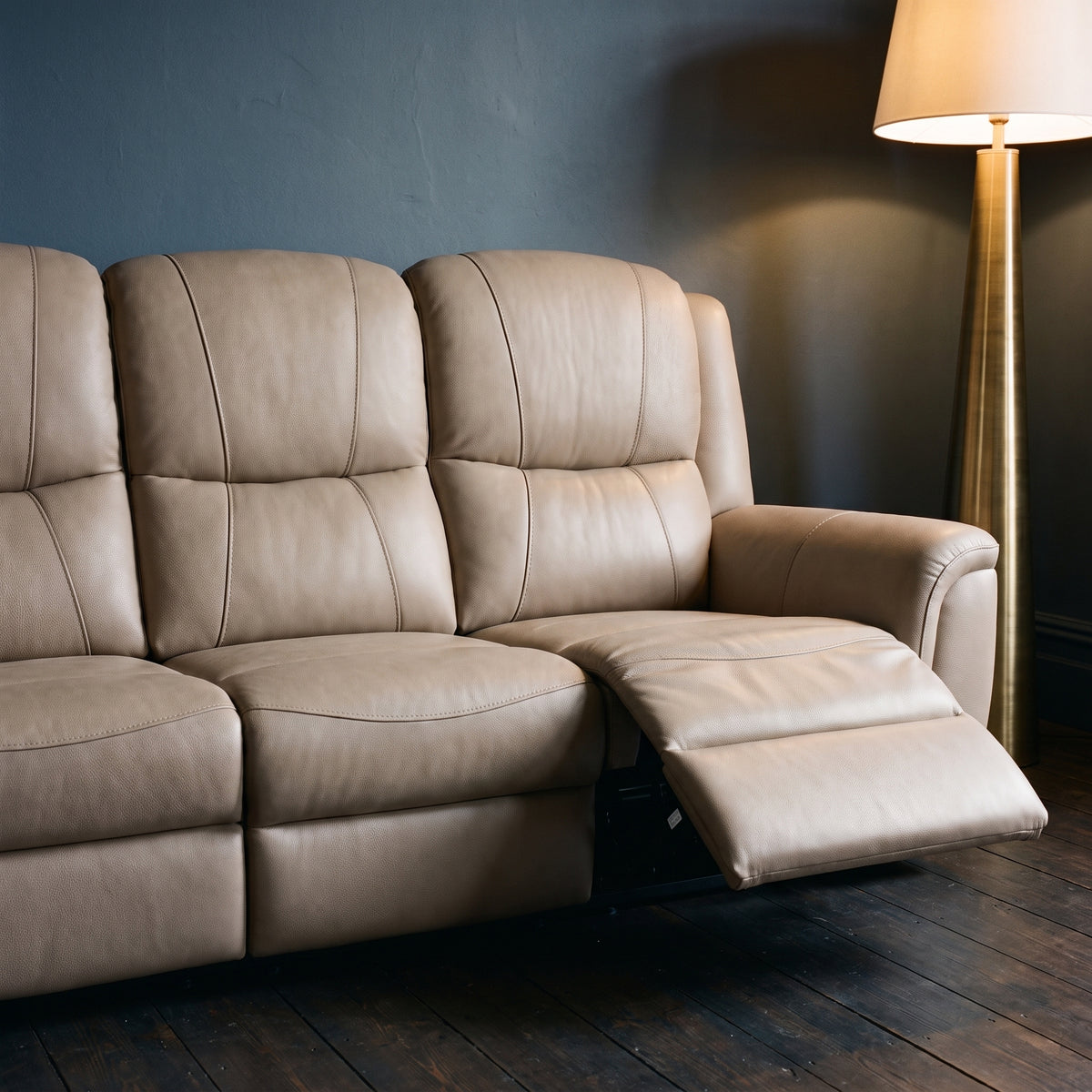 Sydney reclining sofa with one footrest extended, against deep slate blue walls with dark floorboards