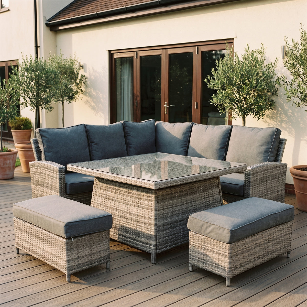 Maldives rattan corner garden set on a decked terrace beside bifold doors and potted olive trees