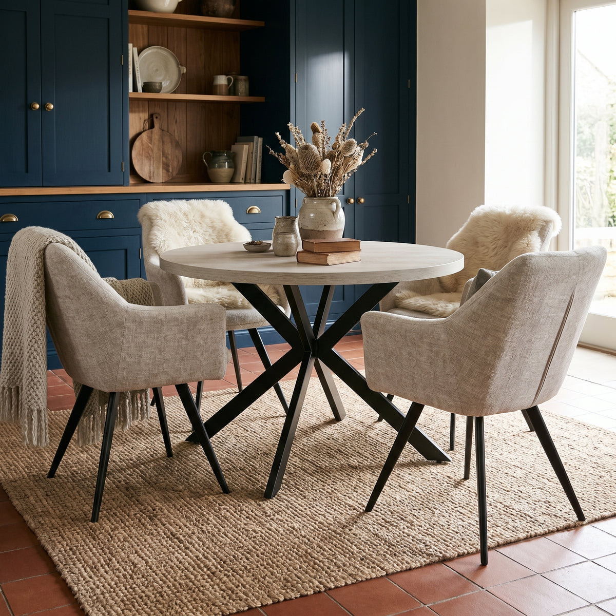 Rodrigo round dining set in a kitchen diner with deep navy cabinets and a terracotta tiled floor