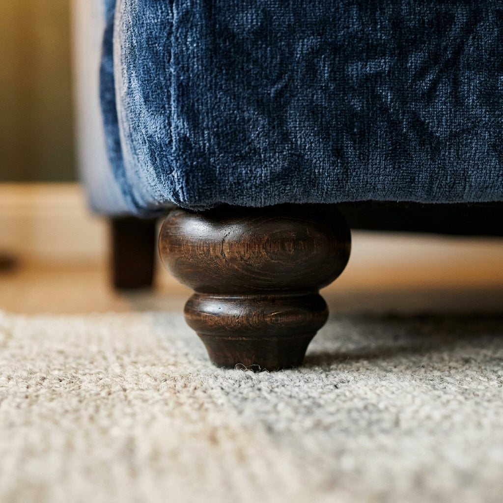 Close up of the dark turned wooden bun foot and navy chenille on the Ellise sofa