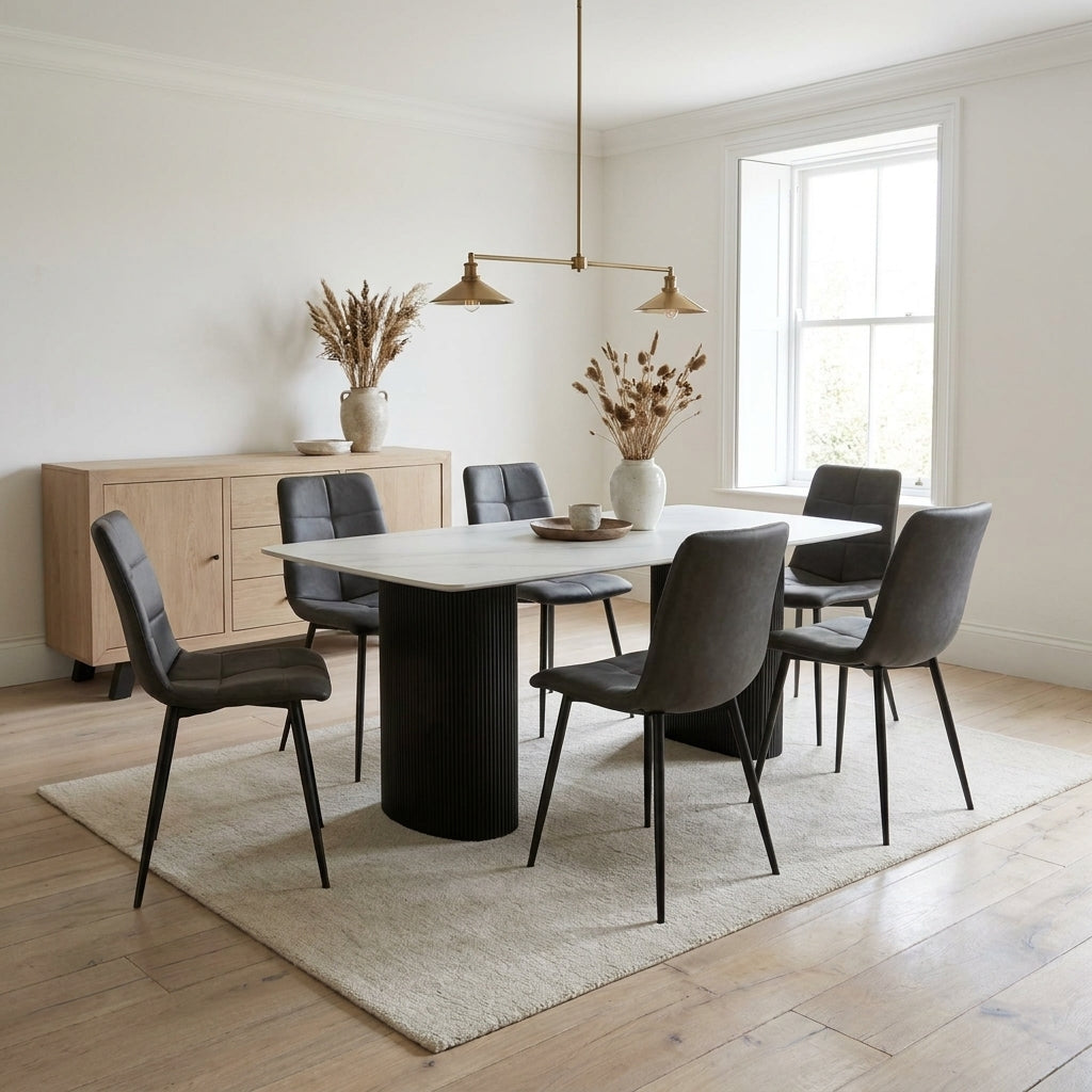 Moet seven piece dining set with a pale ceramic top and black fluted pedestal in a bright white dining room