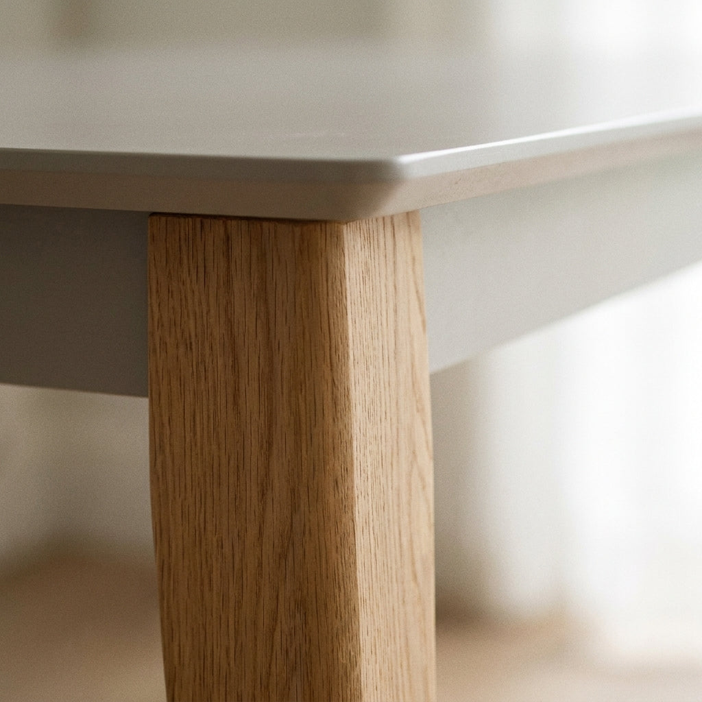 Close up of the chunky tapered solid oak leg and taupe top on the Brianna dining table