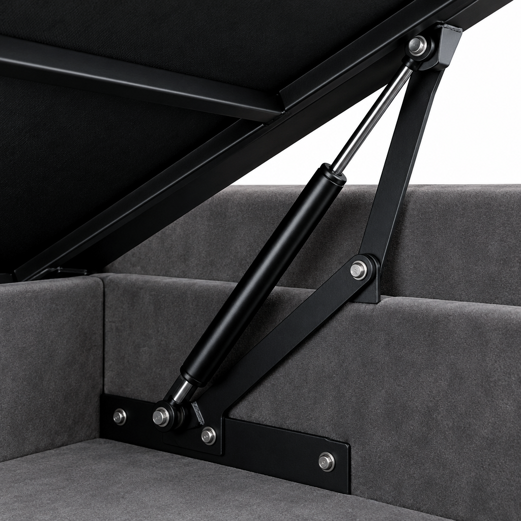 Close-up of the Galgorm ottoman bed lifting mechanism, showing the black gas strut and hinge linkage against the grey velvet base and lined storage well