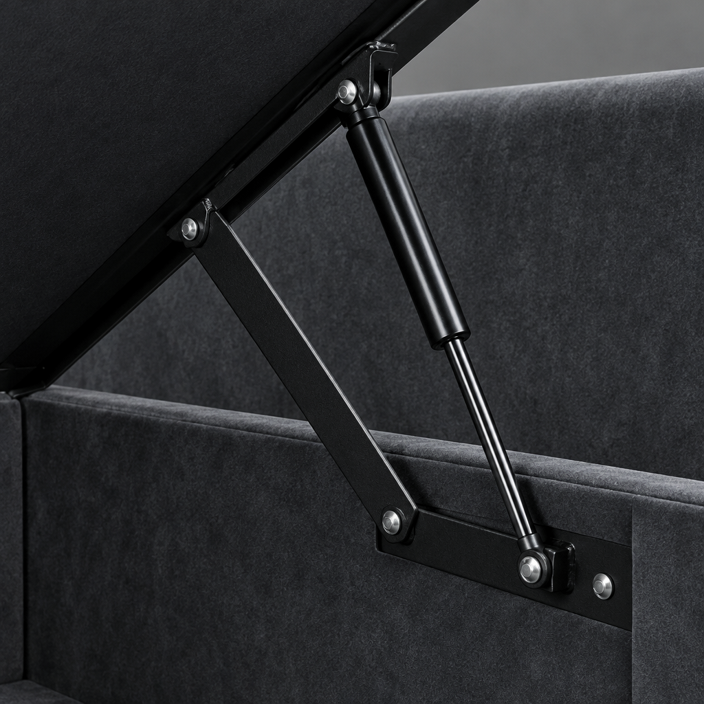 Close-up of the Lisbon ottoman bed lifting mechanism, showing the black gas strut and hinge linkage against the charcoal velvet base and lined storage well