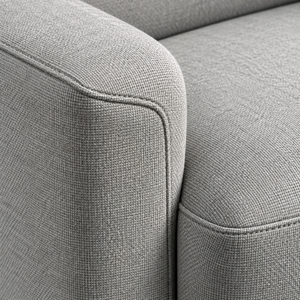 Close detail of the Lynn sofa arm and seat cushion showing the light grey woven fabric and piped seams