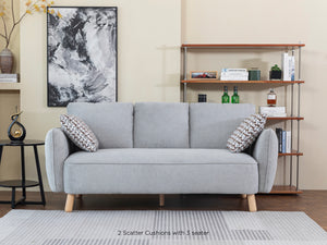 A gray fabric Cassandra sofa with light oak feet, positioned in a room with a wooden floor, a black and white picture on the wall, and a bookshelf in the background.