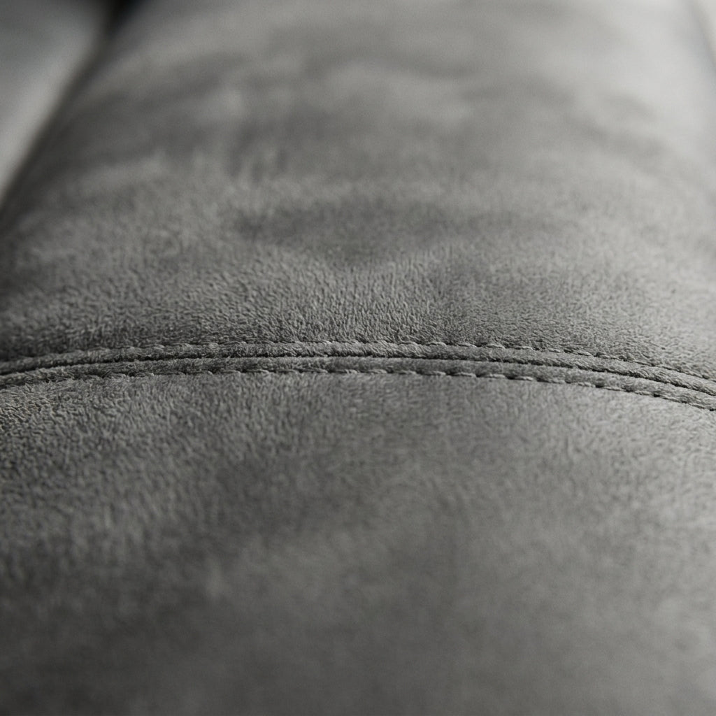 Close-up of gray suede couch upholstery featuring detailed double stitching for a modern, textured living room aesthetic.