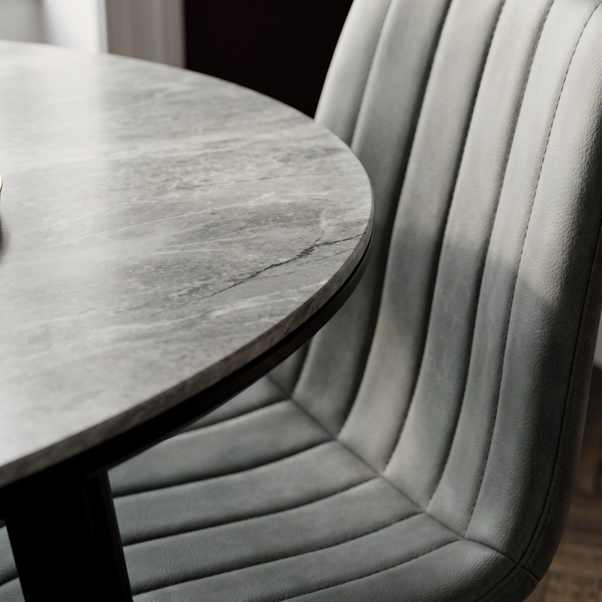 Close up of the Sardinia table edge showing the veined grey sintered stone and the channel stitched grey faux leather chair back alongside