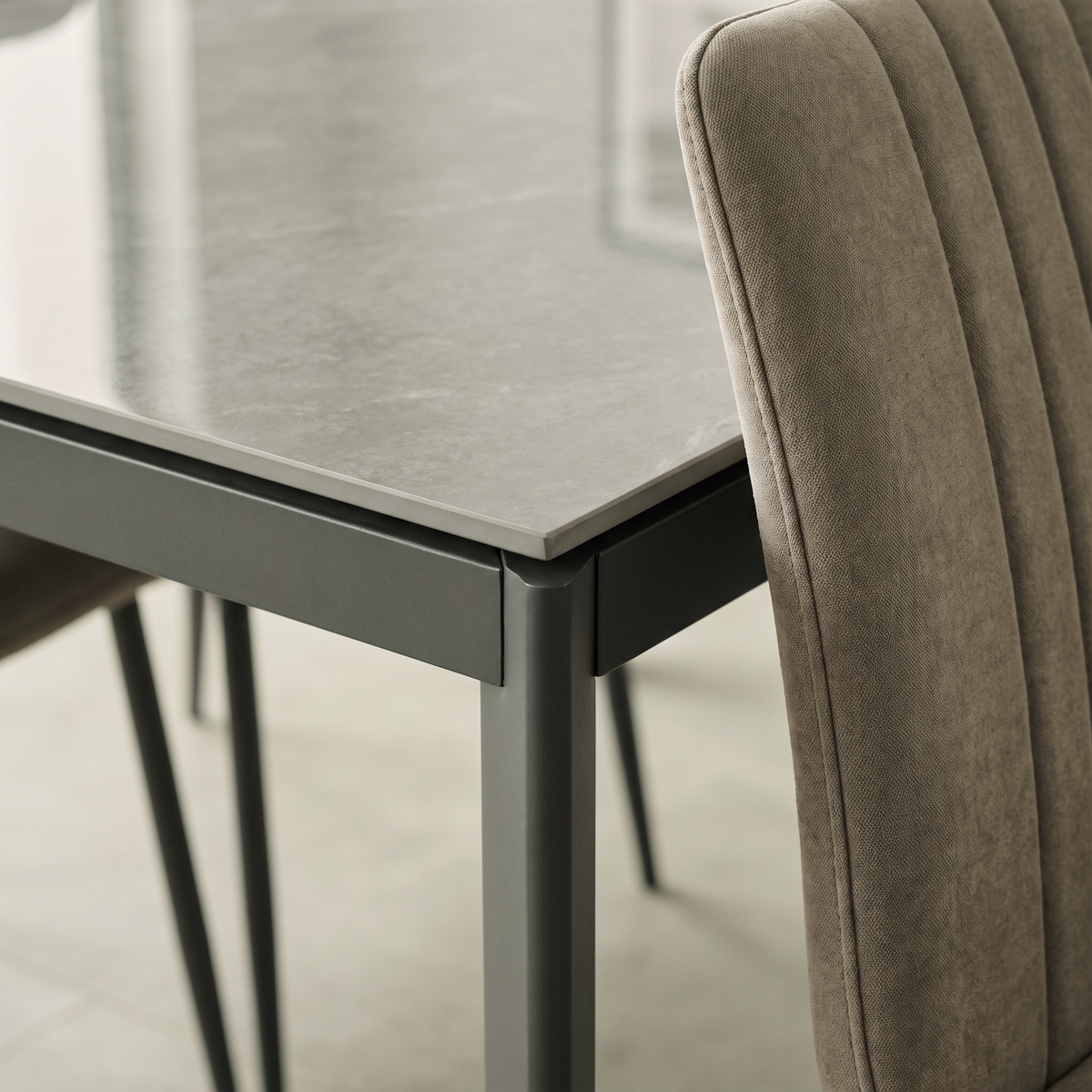 Close up of the Christina table corner showing the high gloss grey sintered stone top, its slim edge and the dark metal frame beneath
