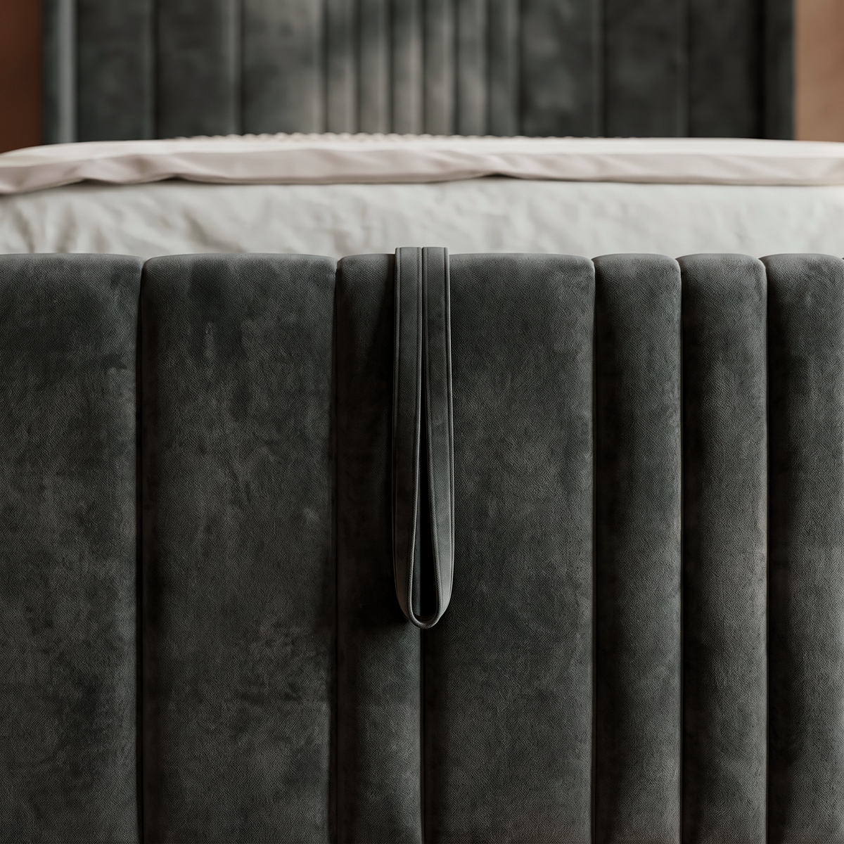 Close up of the Lisbon footboard showing the fabric pull handle that lifts the ottoman base, set into the channelled charcoal velvet