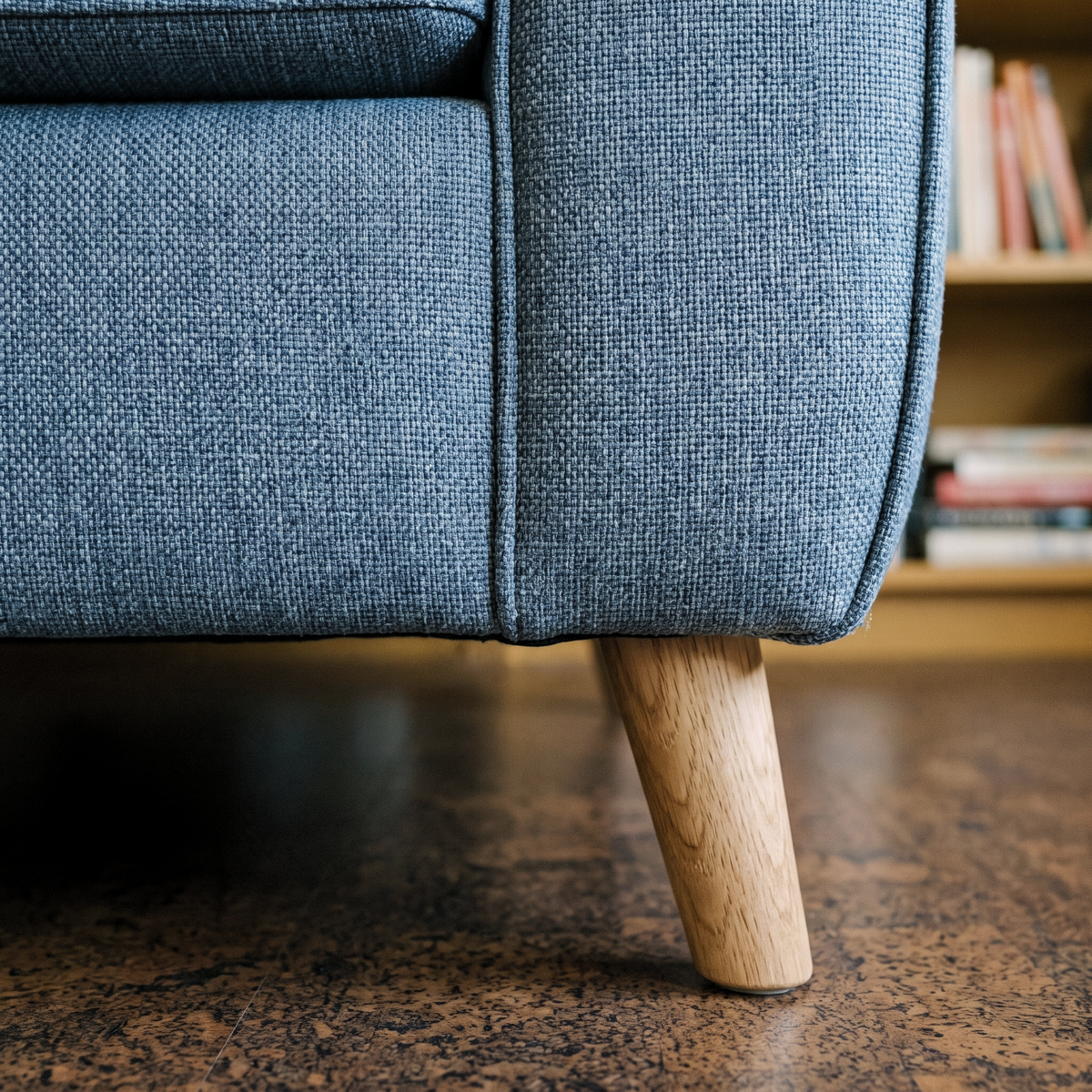 Close up of the denim blue weave and light oak splayed leg on the Optimus sofa bed