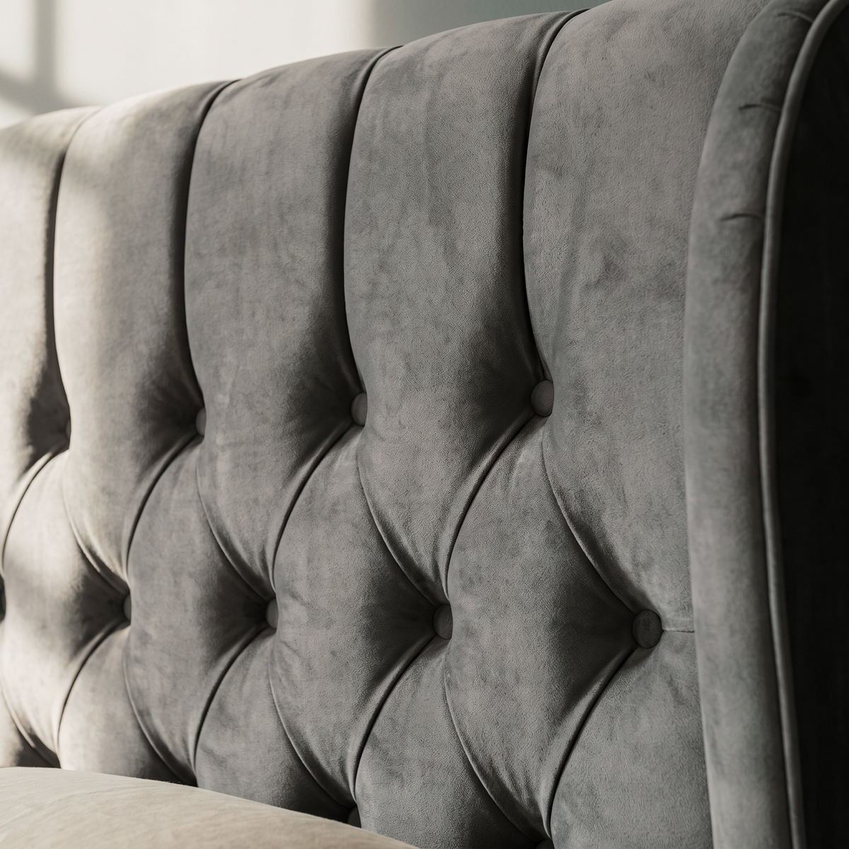 Close up of the deep button tufting and grey velvet pile on the Luxor ottoman bed headboard