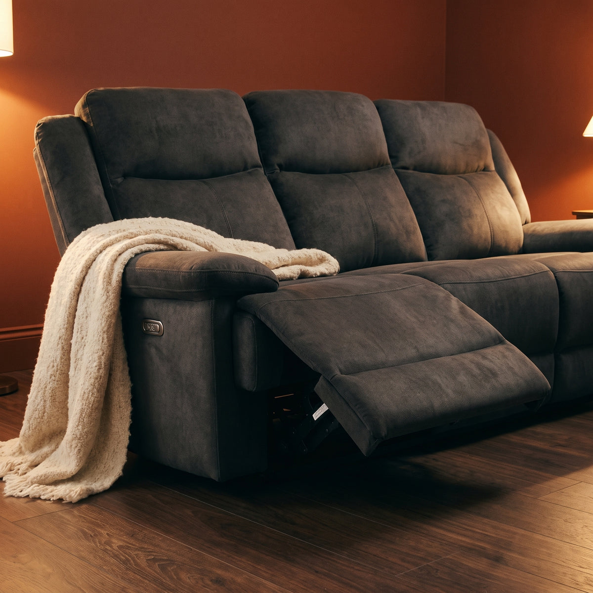 Ash three seater with one footrest extended, against deep terracotta walls with dark walnut flooring