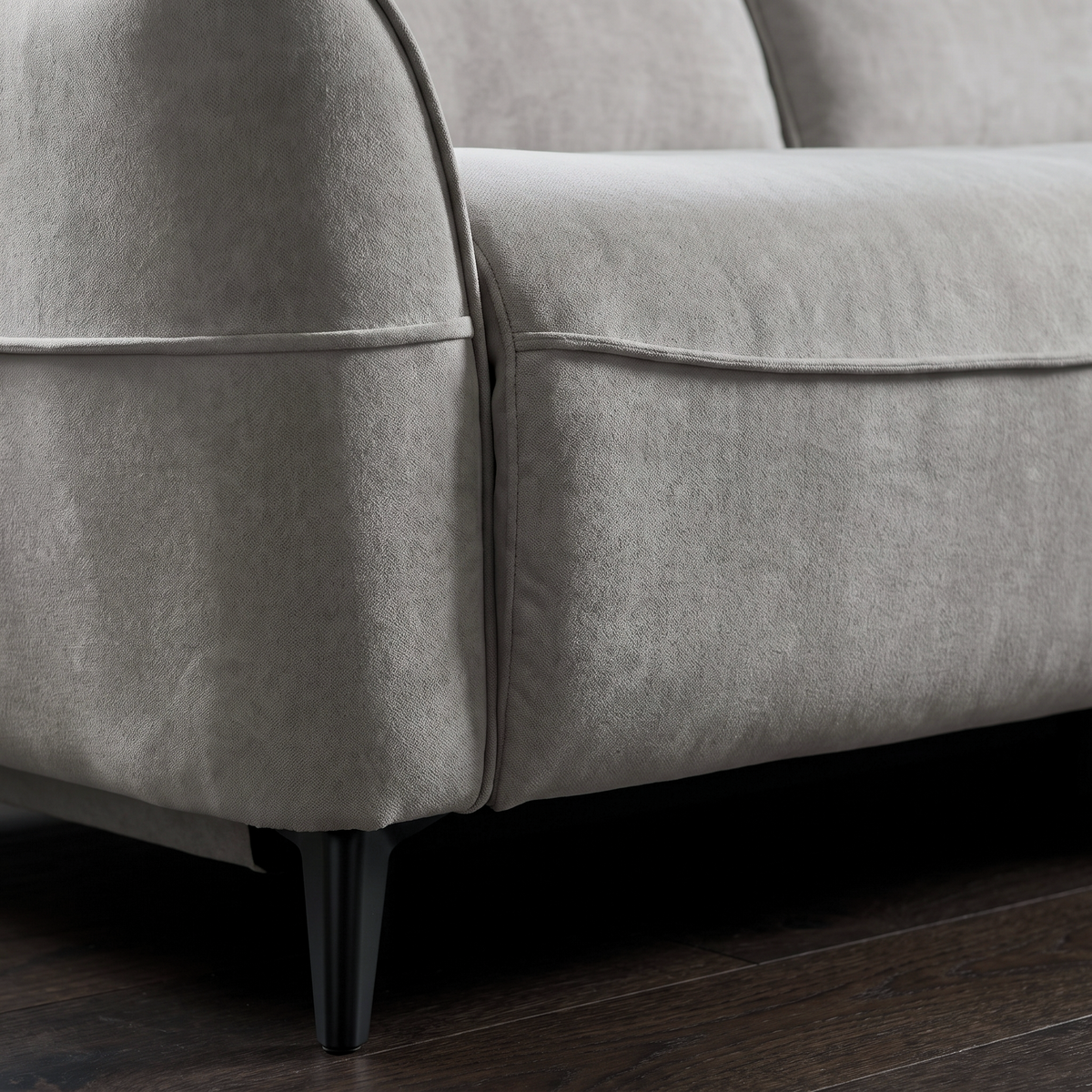 Close up of the piped seat edge and slim black splayed metal leg on the Dune recliner