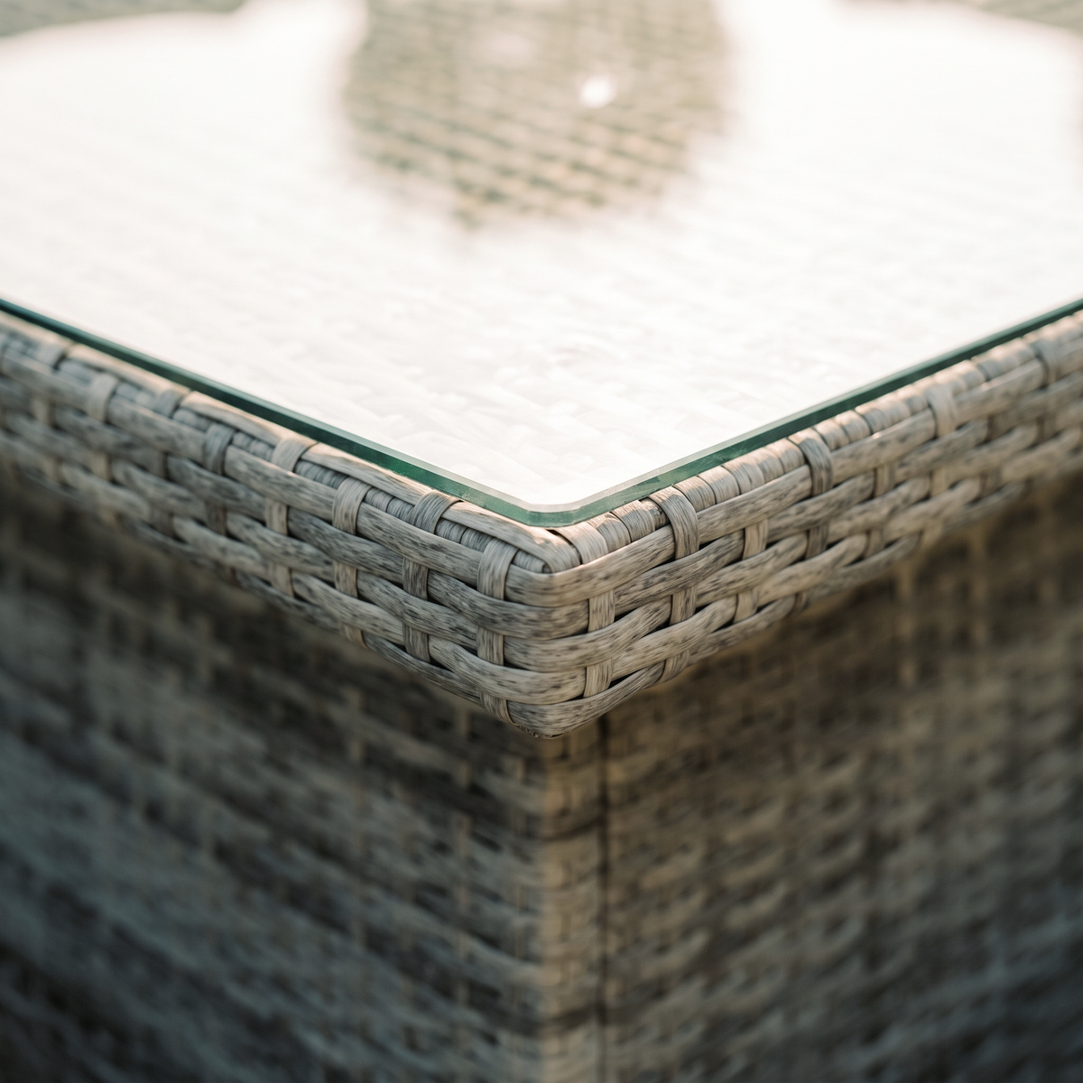 Close up of the glass table top edge and grey rattan weave on the Maldives garden set