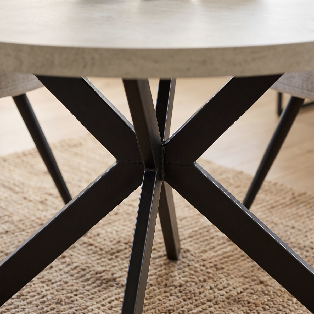 Close up of the black crossed spider base and stone effect table edge on the Rodrigo dining table