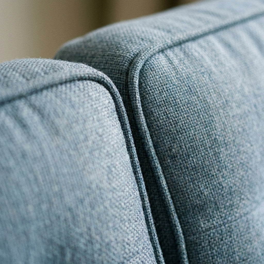 Close up of the piped seam between the back cushions in denim blue fabric on the Optimus sofa bed