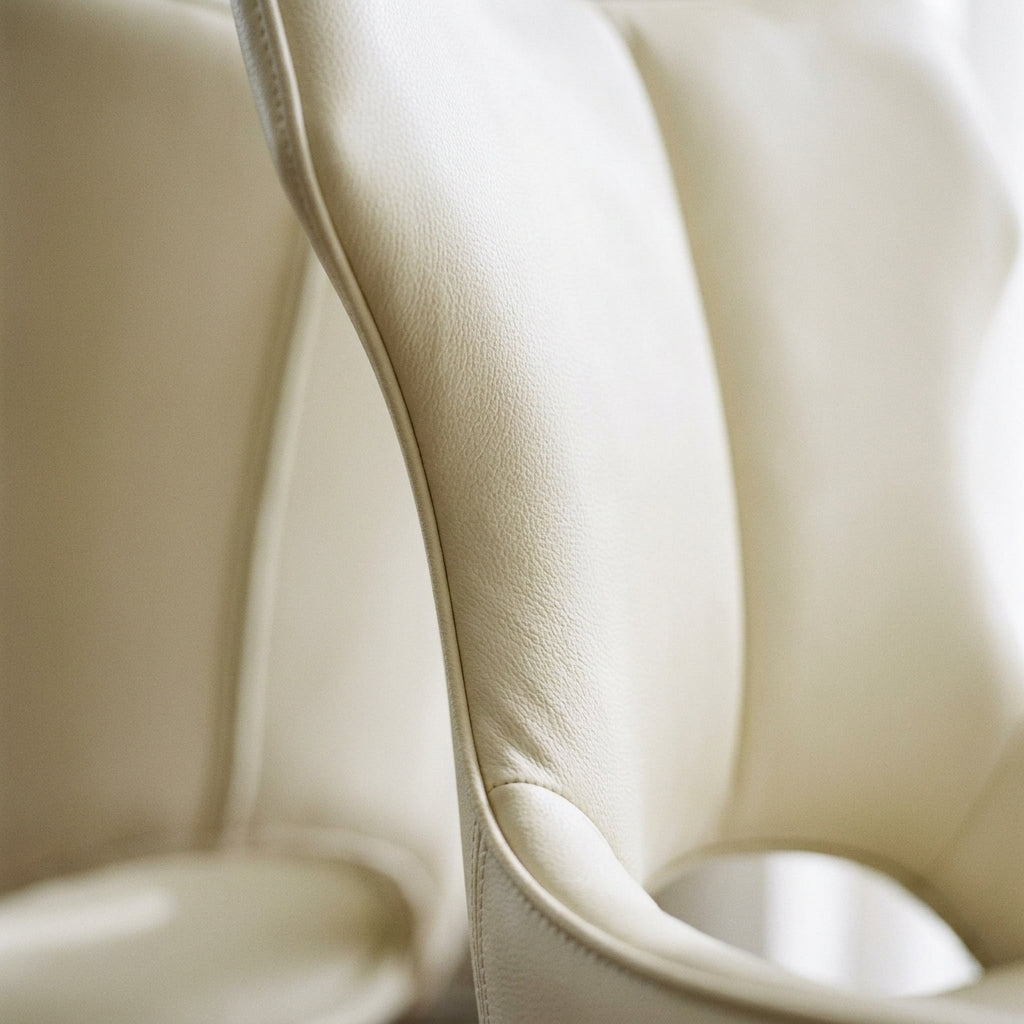 Close up of the curved cream leather look back shell of an Aramis dining chair