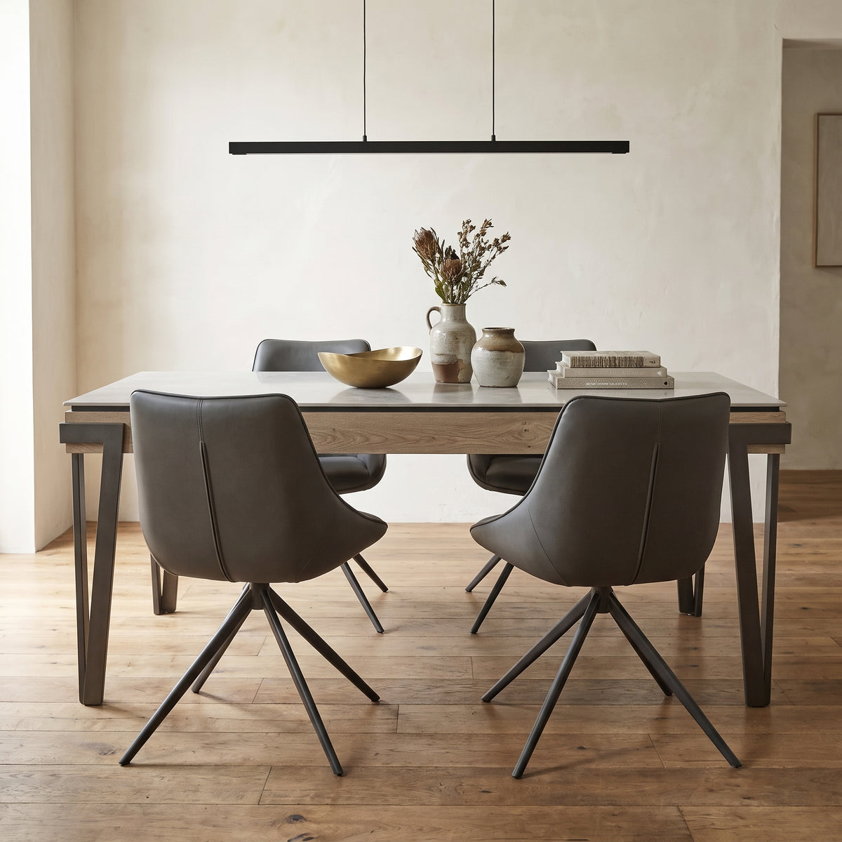 Giorgio five piece dining set with a pale ceramic top and four dark grey swivel chairs in a contemporary dining room