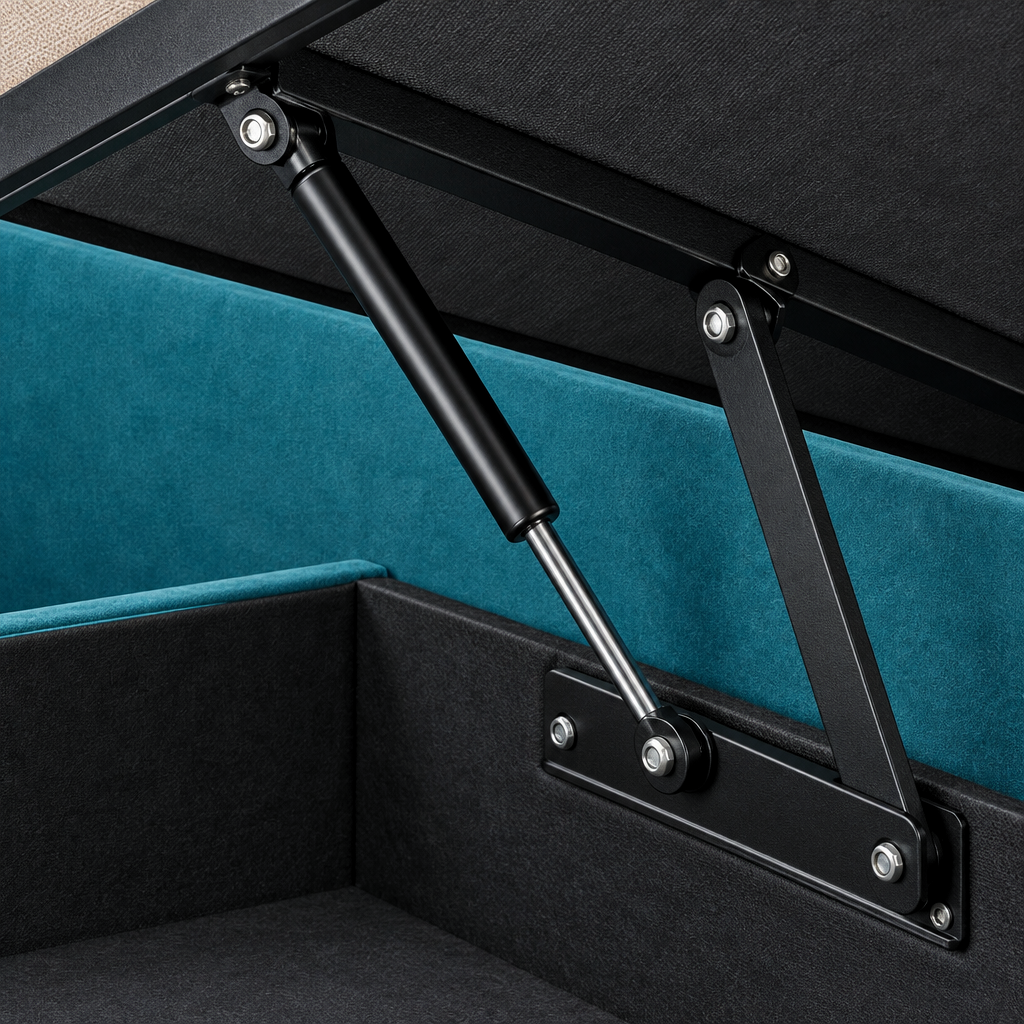 Close-up of the Juan ottoman bedframe lifting mechanism, showing the black gas strut and hinge linkage against the teal upholstered base and lined storage well