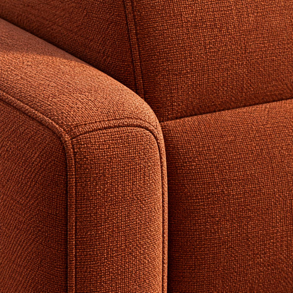Close detail of the Natasha sofa arm and back in rust orange fabric, showing the weave and the piped seam